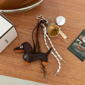 Detail of leather dachshund keychain with mini baseball accessories on wood background