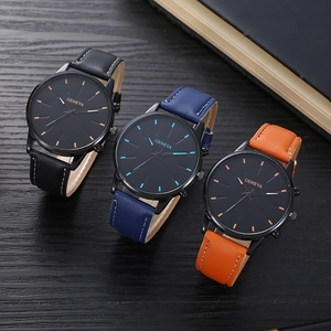 Close-up of three minimalist leather watches with black dials on dark wood table