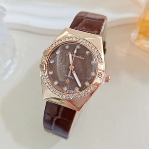 Detail of rose gold case with crystal bezel and brown star dial on leather strap watch