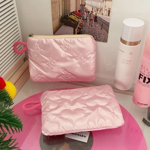 Close-up of pink quilted satin pouch with heart and bow patterns and smooth metal zipper