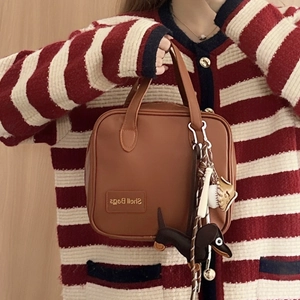 Brown leather handbag with cute dachshund charm and accessories on wood background