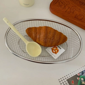 Close-up of oval stainless steel mesh basket holding croissants on a white tabletop