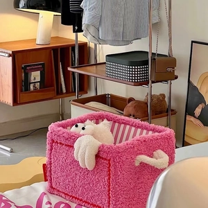 Detail of pink plush storage basket with white handles and striped lining for toy storage