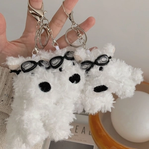 Detailed view of three white plush Westie keychains with goggles and metal lobster clasps