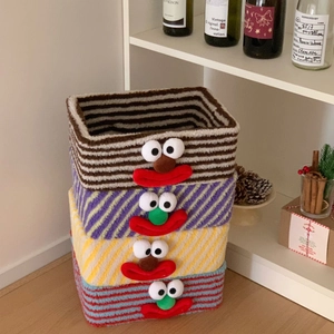 Detail of four stacked lamb wool storage baskets with colorful knitted clown faces