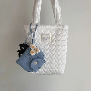 Détail du sac matelassé à cœurs blancs avec pochette nuage bleu et breloque ours