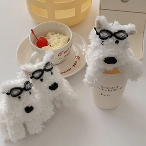 Close-up of cute plush Westie dog keychains wearing stylish pilot goggles on a table