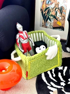 Detail of green plush storage basket showing soft texture and white fleece handles