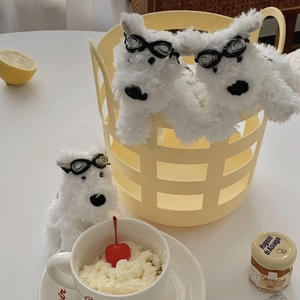Close-up of white plush Westie puppy charms with black goggles and fluffy curly fur texture