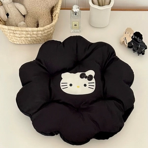 Detail of flower-shaped black cushion featuring a white cartoon kitty face and soft texture