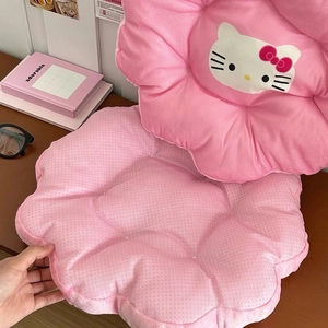 Detail view of pink flower-shaped Hello Kitty plush cushions on a dark wooden table