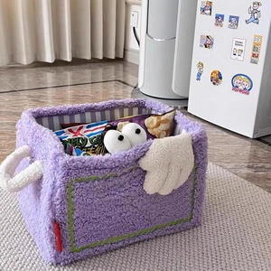Detail of purple plush storage basket with cartoon eyes and snacks inside on a soft rug
