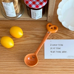 Close-up of cute bread-shaped ceramic spoon with a smiley face on a wooden desk