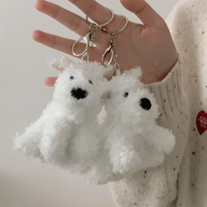 Close-up of two fluffy white Westie dog plush keychains with silver metal hooks