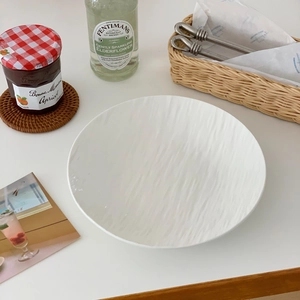 Detail shot of a minimalist white ceramic dinner plate with textured relief tree ring pattern