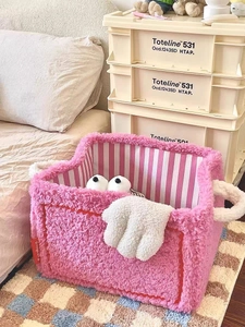 Close-up of a pink plush storage basket with cute 3D eyes and striped interior lining