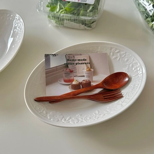 Vintage oval white embossed ceramic plate set with rustic wooden spoon and fork