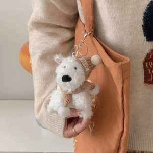 Plush Westie puppy keychain with brown knitted hat and scarf on an orange canvas bag