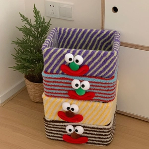 Detailed stack of colorful striped plush storage baskets with cartoon faces for desk