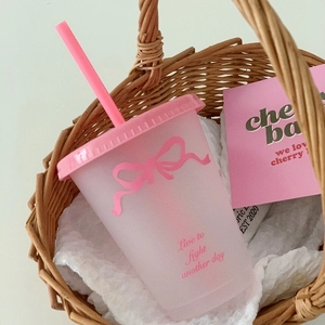 Roze matte beker met rietje voorzien van een strikpatroon en tekst in een mandje