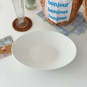 Close-up of vintage white oval ceramic plate with elegant embossed floral rim patterns