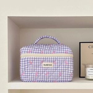 Detailed view of purple checkered quilted vanity bag with pink bow embroidery and handle