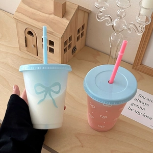 Matte gradient blue and pink plastic straw cups with cute bow designs on wooden table