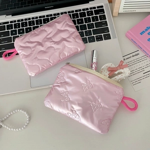 Detail of pink quilted makeup bags with heart and bow patterns in a cozy setting