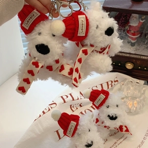 Detailed close-up of a plush Westie keychain wearing a red knitted hat and scarf