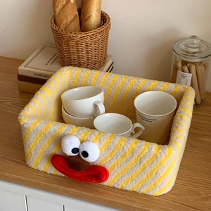 Striped fleece storage basket with cute clown face on a warm wooden tabletop