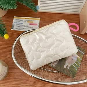 Close-up of heart quilted makeup bag with pink knotted zipper pull in a decorative basket