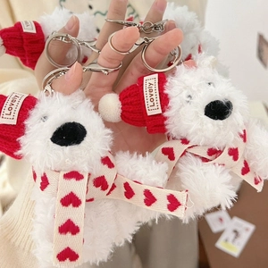 Close-up of plush white bear keychain with red knitted hat and heart pattern scarf