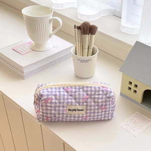 Detailed view of purple checkered quilted pencil case with soft bow pattern and brand label