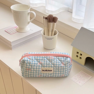 Close-up of blue plaid quilted pencil case with pink bow embroidery and zipper detail