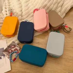 Flat lay of colorful silicone makeup bags with zippers and lanyards on a soft rug