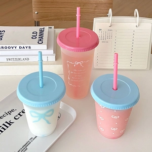 Three aesthetic plastic straw cups with bow patterns and lettering on a desk