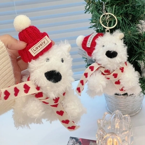 Close-up of plush dog keychain wearing a red knit hat and scarf on a Christmas tree