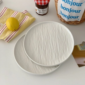 Close-up of stackable white ceramic plates with unique vertical water ripple texture