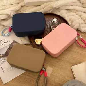 Flat lay of colorful silicone cosmetic bags with rope handles on a wooden surface
