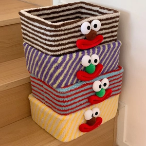 Detailed view of four colorful striped knit storage baskets with cartoon clown face designs