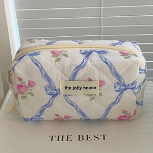 Gros plan sur la trousse à maquillage matelassée avec roses roses et rubans bleus