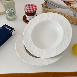 Close-up of minimalist white ceramic plates with textured wide rims and glossy glaze finish