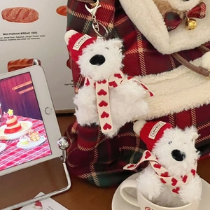 Close-up of plush dog keychain wearing a red knit hat with heart scarf detail
