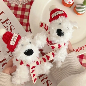 Detail of two plush white puppy keychains wearing red knit hats and heart scarves