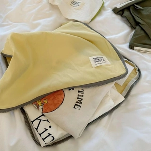 Light yellow nylon travel storage bag with zipper for organizing clothes on white bedding