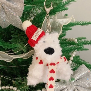 Mini plush polar bear keychain with red knit hat on a festive Christmas tree branch