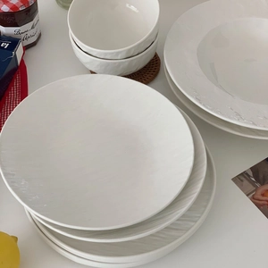 Detail of white ceramic dinnerware set featuring embossed radial textures and matte finish