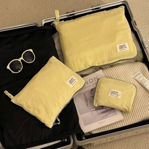 Three-piece light yellow linen texture travel organizers inside a silver suitcase