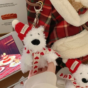 Mini plush Westie dog with red Christmas hat and scarf hanging on a cute plaid bag