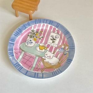 Overhead view of hand-painted ceramic plate featuring a cute cat and floral table design